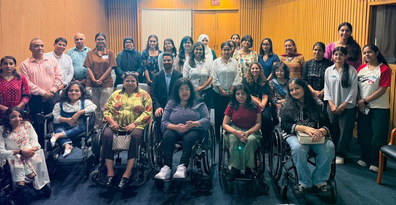 Participants, several of them wheelchair users, seated together in a circle at an in-person dialogue.